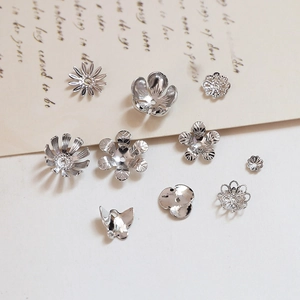 Detailansicht silberner Blumen-Perlenkappen und hohler Abstandsperlen für DIY-Schmuck