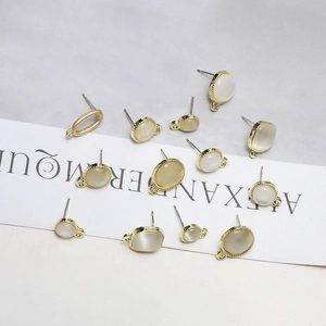 Macro detail of gold DIY earring components with cat-eye stone inlays and ring loops