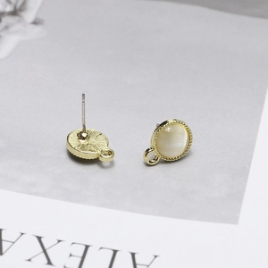 Detailed macro view of gold-plated cat eye stone earring studs with hanging loops