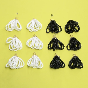 Detail of beaded tassel pendants with golden caps in black and white for DIY jewelry