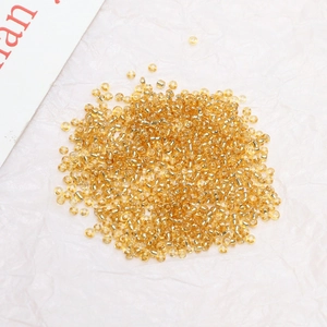 Macro shot of 2mm silver-lined golden glass seed beads for DIY jewelry making