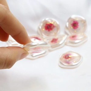 Détail d'une perle en résine pour boucle d'oreille avec fleur rouge et feuille d'or