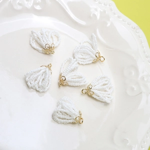 Close-up of elegant white bead fan tassels with golden floral caps for DIY jewelry