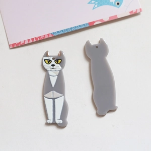 Detalle de colgantes de acrílico con forma de gato, rayas grises y acabado artístico