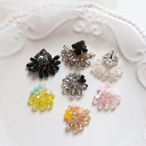 Macro shot of 7 styles of crystal beaded charms for handmade earrings on white lace
