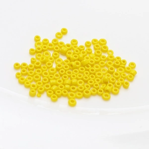 Macro shot of 2mm bright yellow ceramic seed beads for DIY jewelry and beaded handicrafts