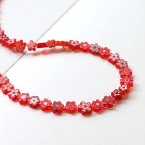 Vue détaillée de perles fleurs en verre rouge disposées en courbe pour bijoux DIY