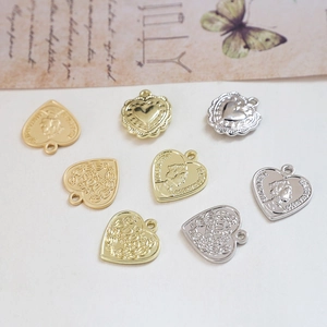 Makro-Detail von herzförmigen Vintage-Münzanhängern in Gold und Silber für Schmuckherstellung