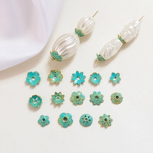 Close-up of vintage flower bead caps in teal enamel and gold plating for jewelry making