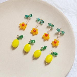 Dettaglio di ciondoli a forma di fiore e limone in perline per creazione gioielli fai-da-te
