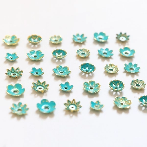 Blue and gold flower bead caps for DIY jewelry making neatly arranged on a white background