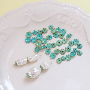 Macro view of blue floral enamel bead caps with gold gilding for DIY jewelry making