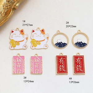 Detail van verzilverde legering bedels met Maneki Neko kat en perzikbloesem geluksamuletten