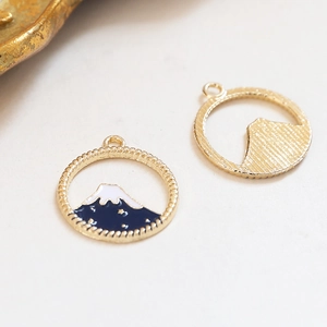 Close-up van Mount Fuji-bedeltjes en geborstelde goudtextuur voor DIY-sieraden
