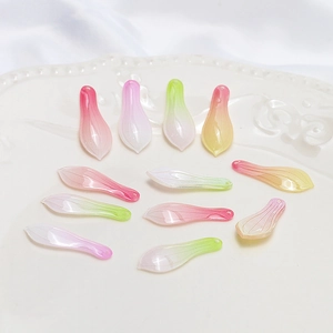 Detailed macro view of gradient resin petal pendants for DIY jewelry crafting on white ceramic