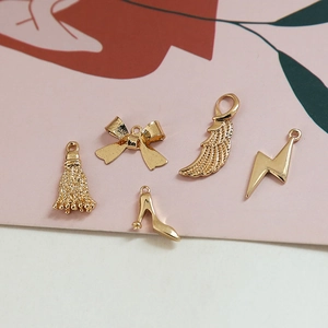 Détail macro de cinq breloques en métal doré, dont talons hauts et forme d'éclair