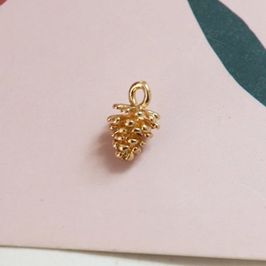 Détail d'un pendentif pomme de pin doré en relief avec texture réaliste et anneau