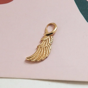 Détail macro d'un pendentif aile d'ange doré montrant la texture des plumes pour bijoux DIY