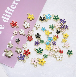 Flache Ansicht bunter Emaille-Blumenanhänger für DIY-Schmuck auf strukturiertem Hintergrund