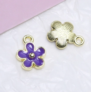 Makroansicht der Vorder- und Rückseite lila Emaille-Blumenanhänger mit Goldbeschichtung