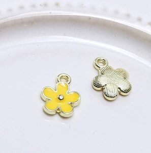 Makroaufnahme: gelbe Emaille-Vorderseite und goldene Rückseite des Blumenanhängers