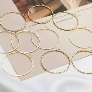 Close-up of golden hollow circle pendants with smooth and twisted textures for DIY earrings