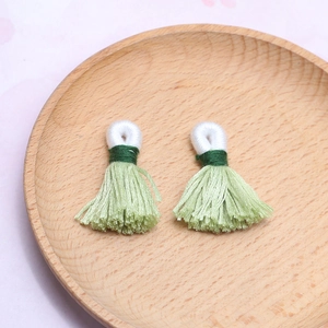 Nahaufnahme hellgrüner handgefertigter Baumwollquasten mit Schlaufen für DIY-Schmuck