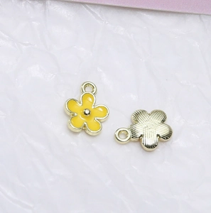 Makro-Detail des gelben Emaille-Blumenanhängers mit goldfarbener Metallstruktur und Öse