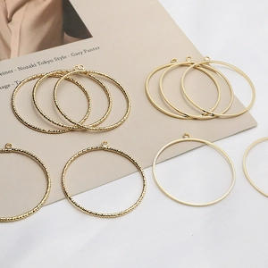 Detailed view of twisted and smooth golden metal ring pendants for DIY jewelry crafting