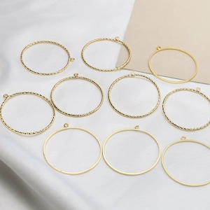 Detailed view of 10 golden hollow circle charms with smooth and twisted textures