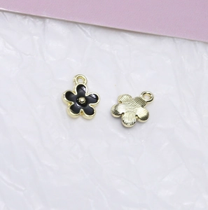 Detaillierte Vorder- und Rückansicht der goldenen Blumenanhänger mit schwarzer Emaille für DIY
