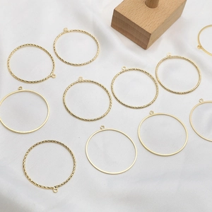 Detail of gold-plated hollow circular pendants with smooth and twisted textures for DIY jewelry