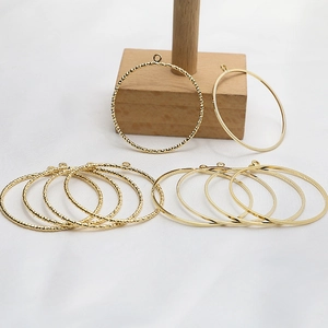 Golden DIY hollow round circle charms with twisted and smooth texture on wooden stand