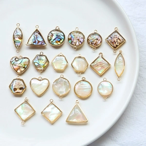 Vue détaillée de breloques géométriques en coquillage doré pour bijoux DIY sur plat