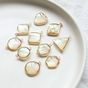 Gros plan de pendentifs géométriques dorés avec nacre naturelle pour bijoux artisanaux