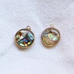 Gros plan de pendentifs ronds en nacre d'abalone plaqué or pour bijoux DIY