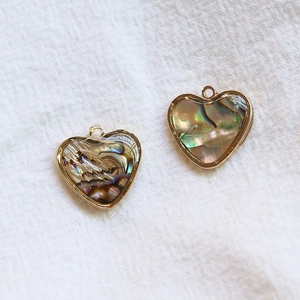 Vue macro de breloques en nacre d'abalone en forme de cœur avec bordure dorée pour bijoux