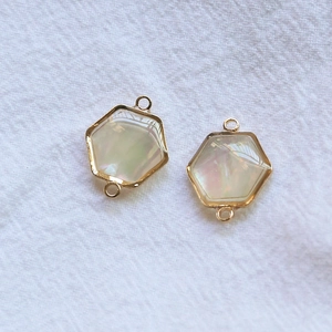 Détail de deux pendentifs hexagonaux en nacre d'abalone plaqués or pour bijoux DIY
