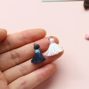 Mini-Baumwollquasten mit Goldringen in der Hand gehalten für DIY Schmuckherstellung Handwerk