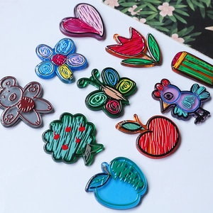 Macro shot of colorful hand-drawn acrylic charms including hearts, birds and flowers