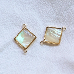Détail macro de pendentifs géométriques en nacre d'abalone avec bords dorés