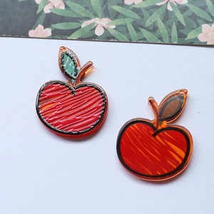 Detailed macro view of two red acrylic apple charms for DIY jewelry and phone accessories