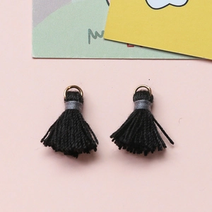 Detail von Mini-Baumwollquasten in Schwarz mit goldenen Metallringen für DIY-Schmuck