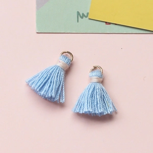 Detailansicht hellblauer Mini-Baumwollquasten mit Goldringen für DIY-Schmuckherstellung