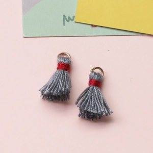 Detailansicht grauer Mini-Baumwollquasten mit goldenen Biegeringen für DIY-Schmuck