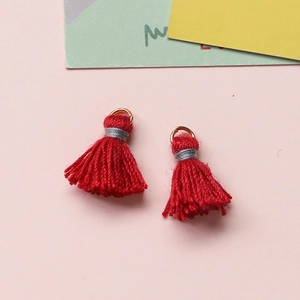 Makroaufnahme roter handgefertigter Baumwollquasten mit Goldringen für DIY-Schmuck