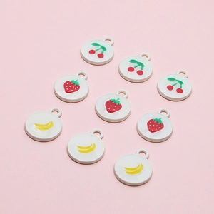 Flat lay of round enamel strawberry cherry banana pendants for DIY jewelry making