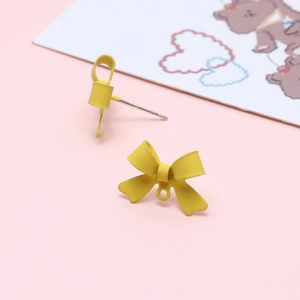 Close-up of matte yellow bow earring studs with DIY hanging loops on pink card