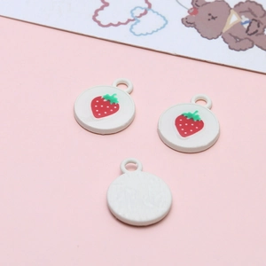 Macro shot of three strawberry charms with red enamel and white base for DIY jewelry