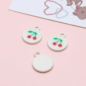 Detail of round alloy pendants with red cherry pattern for DIY jewelry making